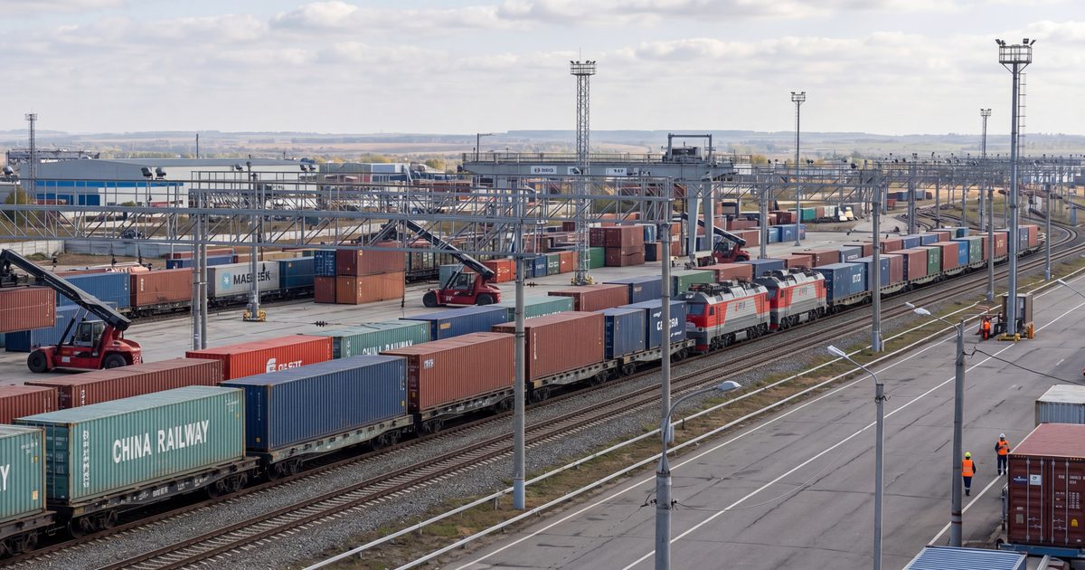 Wide shot of a bustling railway container terminal in Russia, actively processing a long freight train loaded with colorful shipping containers as part of the increased transit flow from China to Europe. The scene captures cranes and reach stackers moving containers from the tracks and storage yards, framed against a wide industrial logic landscape. The horizontal composition is optimized for a news banner, without logos or advertising.
Поезд с контейнерами China Railway на крупном железнодорожном узле в России в марте 2026 года.